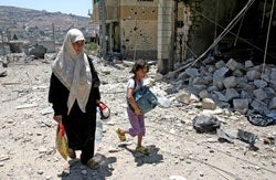 A woman and her daughter walk amidst rubble in the village of Bent Jbeil in southern Lebanon. &copy; 2006 Reuters Ltd.
