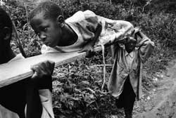 Nine-year-old Katherine is one of the victims of violence in the Democratic Republic of Congo. Her brothers carry her away from the fighting using an old plank as a stretcher. &copy; 2006 Marcus Bleasdale