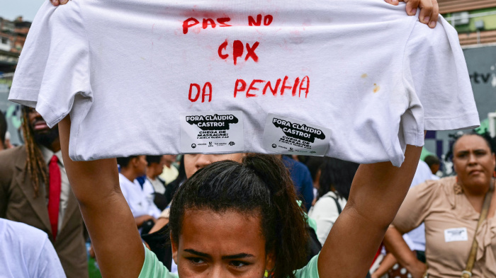 A woman holds up a shirt with a message in Portuguese on it during a protest