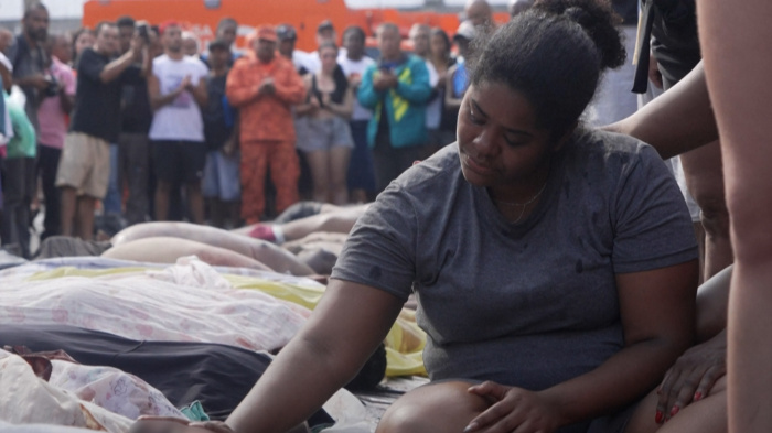 A woman sits among a crowd of people looking down