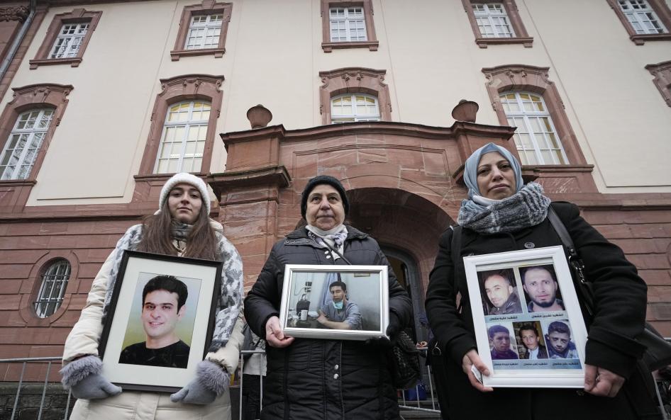 Trois femmes tenaient des photos de proches décédés en Syrie devant le siège du Tribunal régional supérieur de Coblence, en Allemagne, lors de la dernière phase du procès de deux ex-agents des services de renseignement syriens qui s’étaient réinstallés en Allemagne, le 13 janvier 2022.