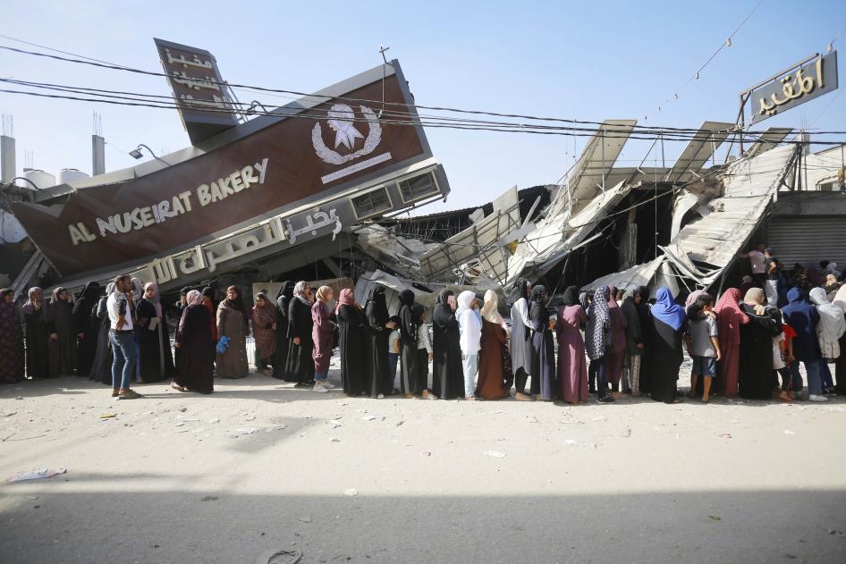 Des personnes faisaient la queue pour acheter du pain devant une boulangerie partiellement détruite, mais toujours opérationnelle, dans le camp de réfugiés de Nuseirat à Deir al Balah, dans la bande de Gaza, le 4 novembre 2023.
