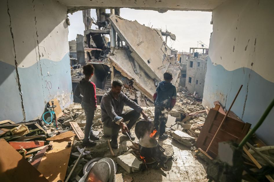 Un habitant du quartier de Khezaa de Khan Younis, dans le sud de la bande de Gaza, assis entre deux jeunes garçons, réchauffait de la nourriture parmi les décombres de son appartement détruit par une frappe israélienne, le 25 novembre 2023.
