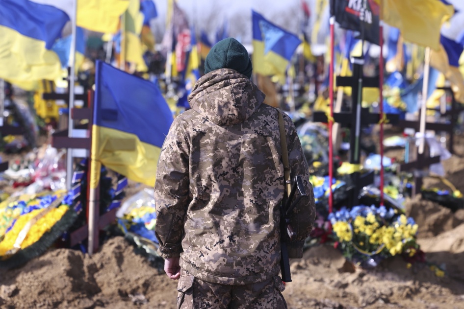 Un soldat ukrainien contemplait les nombreuses tombes de militaires ukrainiens tués lors de la guerre avec la Russie, dans un cimetière rempli de drapeaux ukrainiens à Kharkiv, le 26 février 2024, près de deux ans après l’invasion russe (24/02/22).