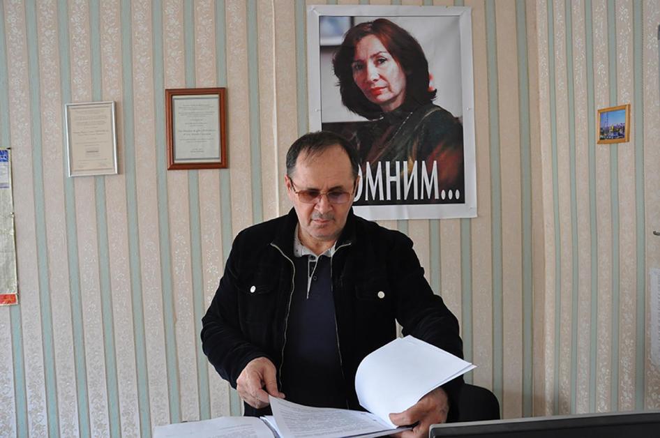 Oyub Titiev stands in front of a portrait of his murdered colleague, Natalia Estemirova, in Memorial's Grozny office.