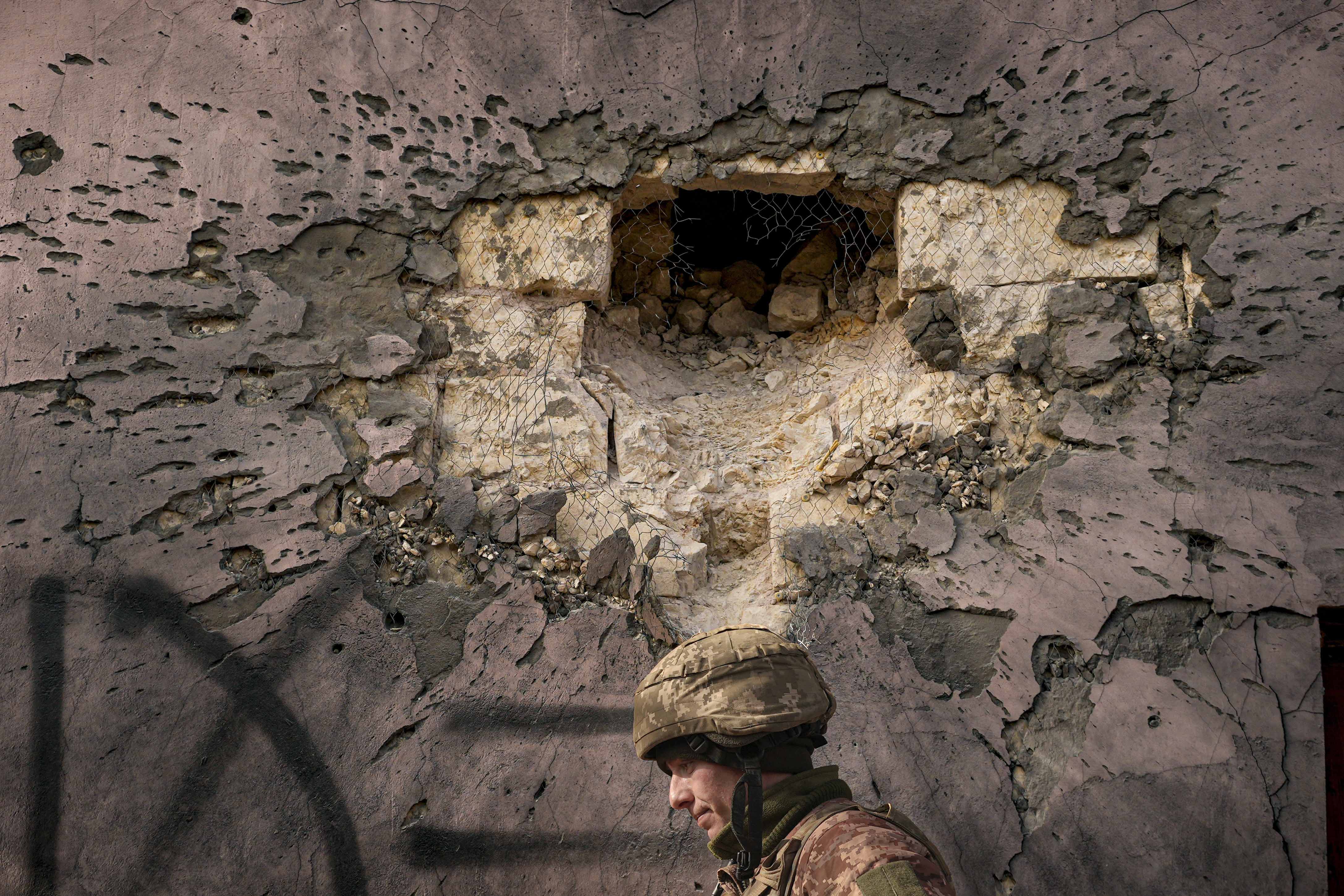 A Ukrainian serviceman walks by a building hit by shelling in Krymske, Luhansk region, in eastern Ukraine, February 19, 2022.