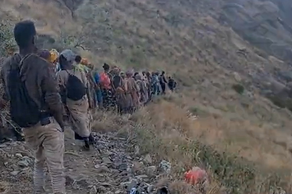 Migrants walking along a steep slope inside Saudi Arabia