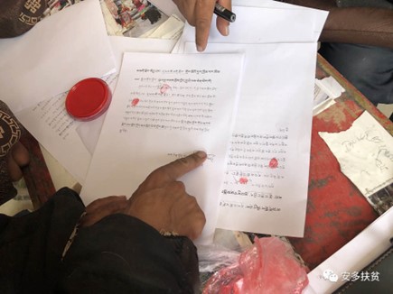 A Tibetan villager puts a fingerprint on an official document