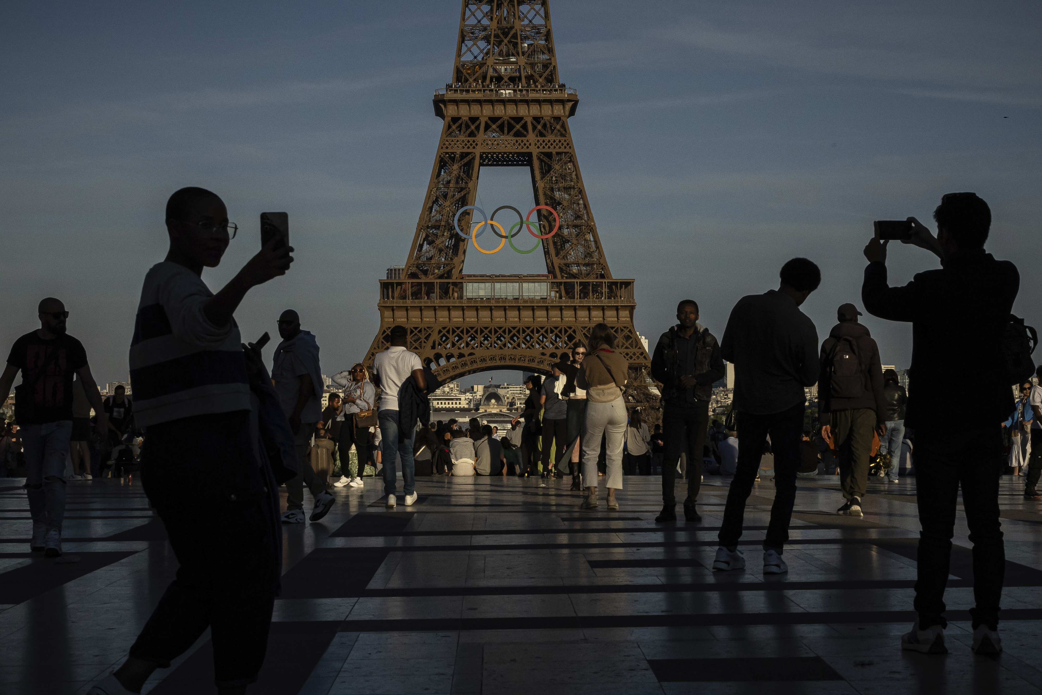 People take photos of the olympic rings at the Eiffel Tower