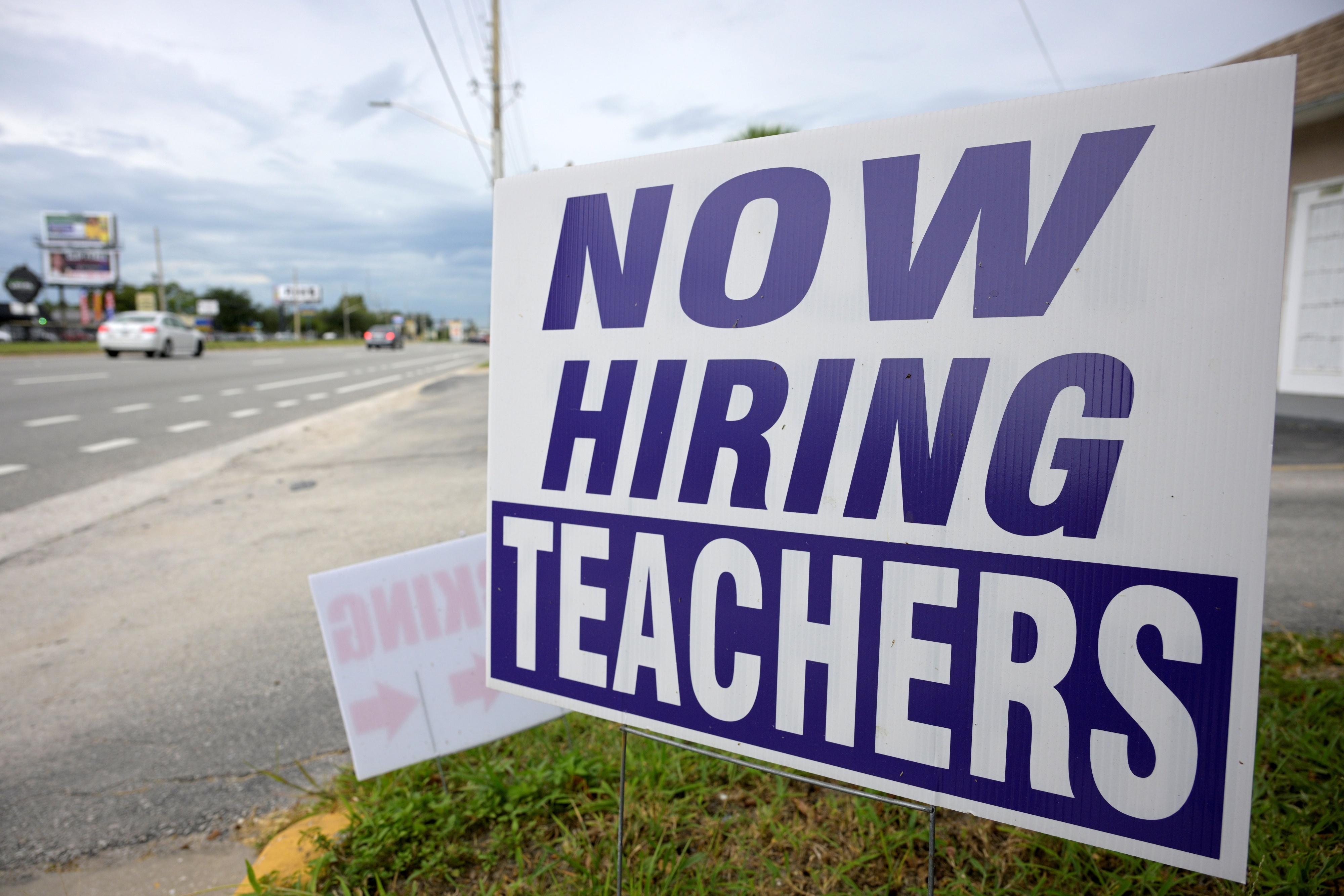A sign by a roadside which reads "Now Hiring Teachers"
