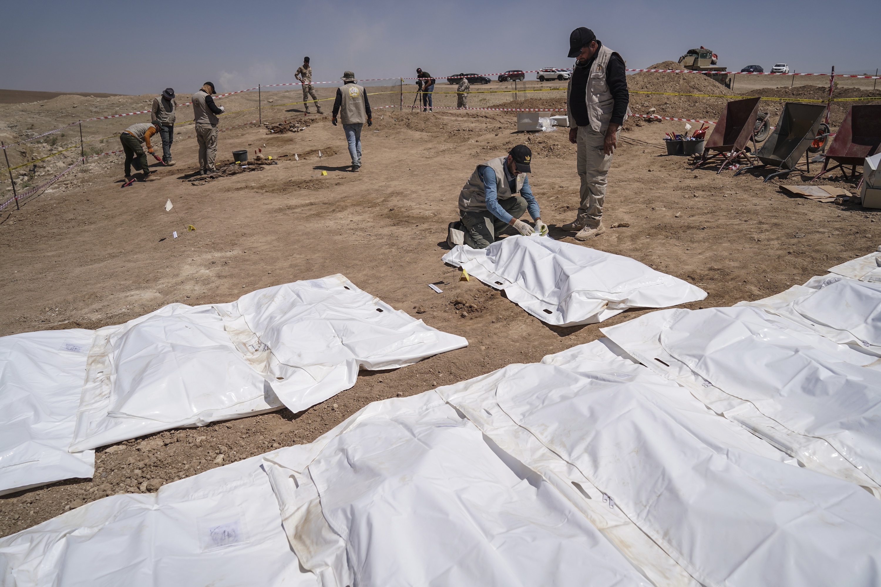 Members of expert teams take part in the opening of a mass grave and the exhumation of the remains of victims who were killed and buried by the so-called Islamic State (ISIS) terror group back in 2014, in Al-Humaydat, Iraq, June 13, 2021.