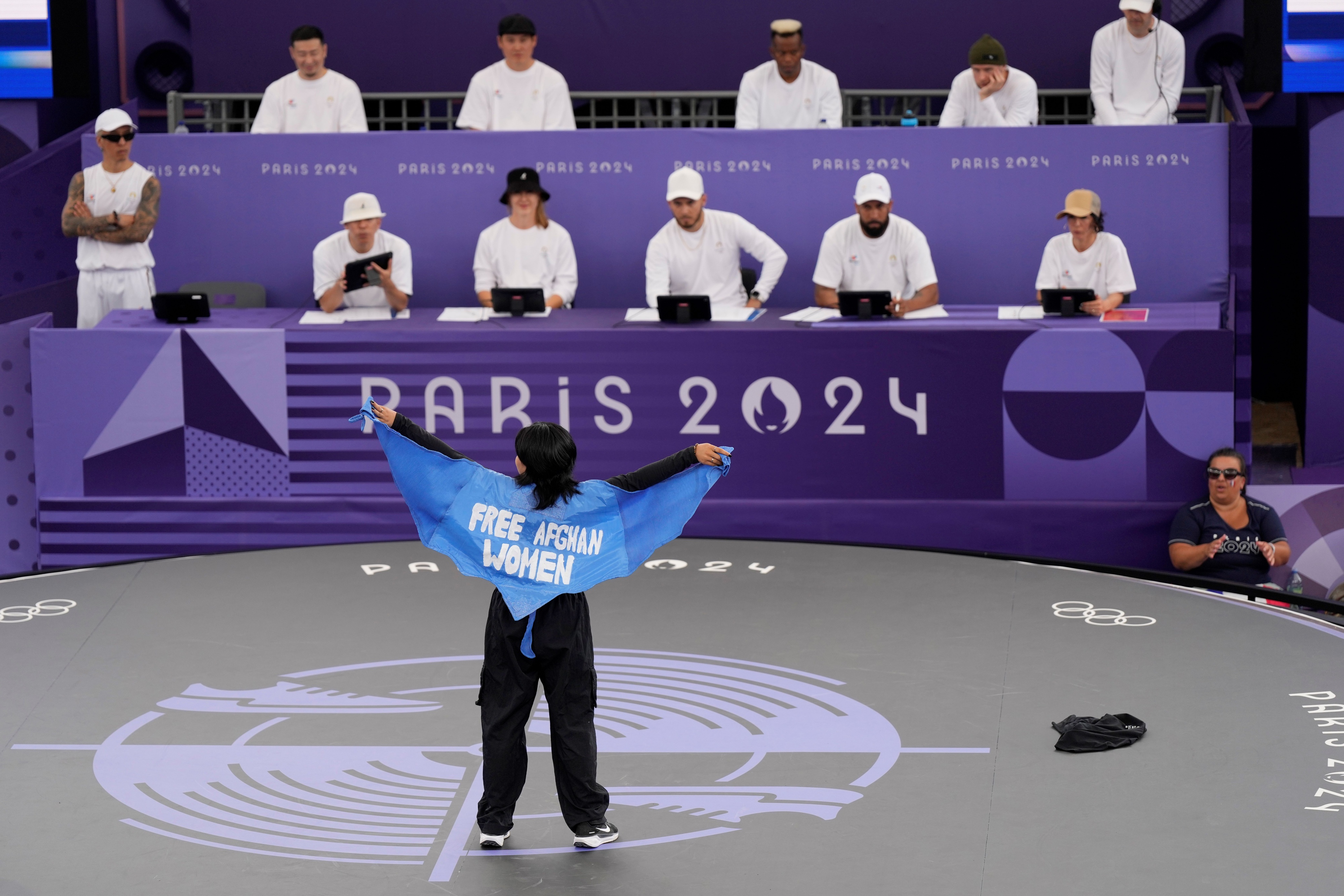 A woman wears a cape that reads "Free Afghan Women" at the Paris Olympics