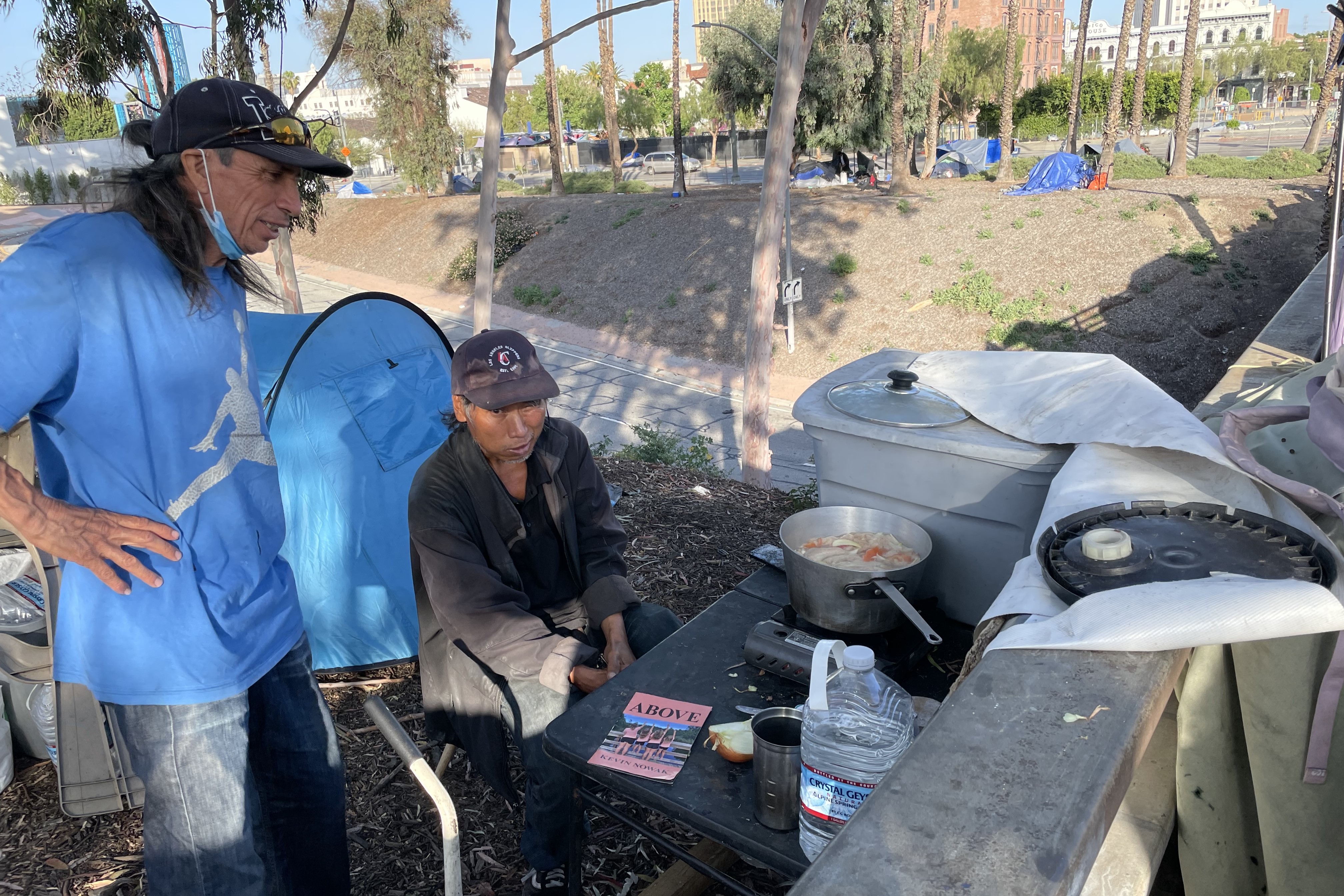 Two men cook a meal outside