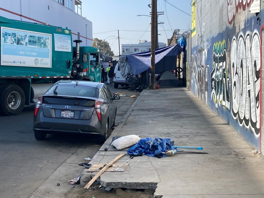 trucks beginning the sweep of a tent encampment.