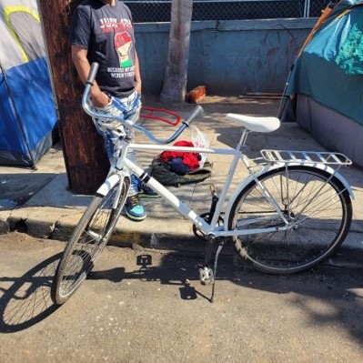 Man standing next to a bike on the sidewalk