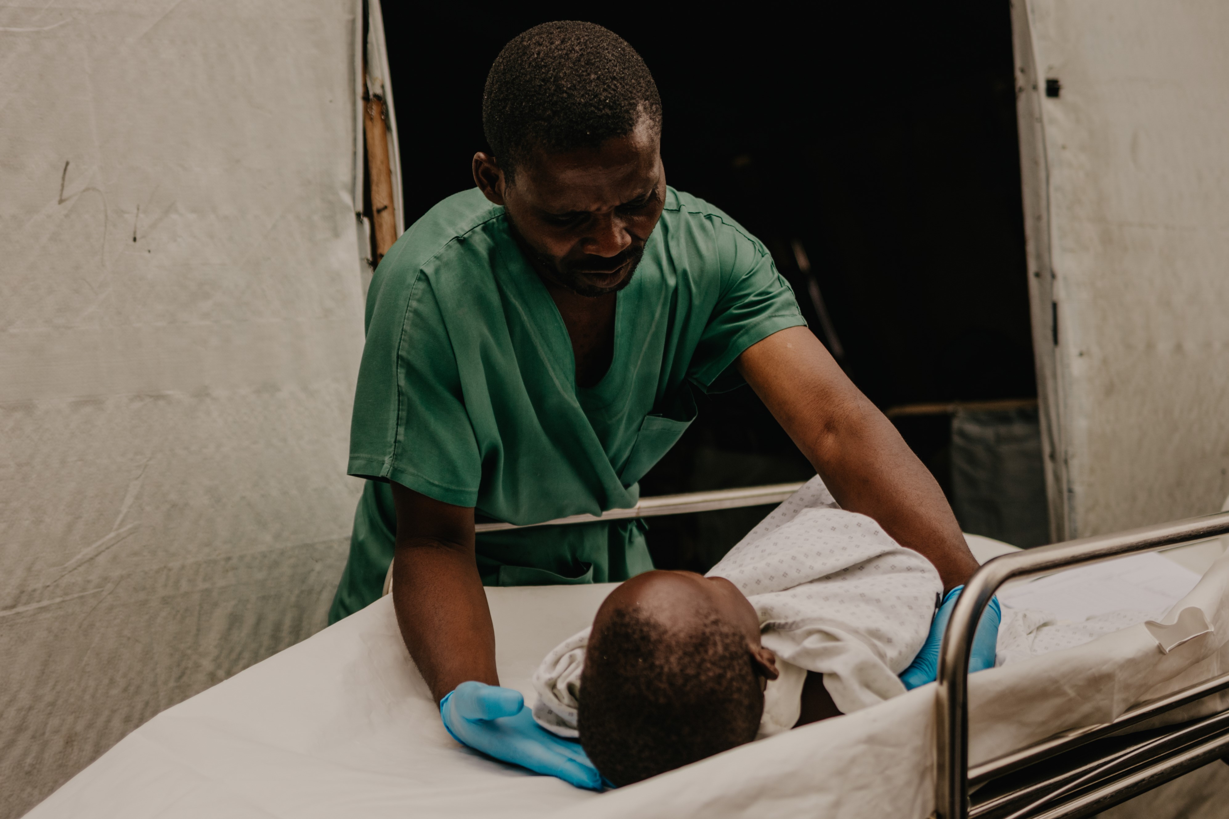 Un membre du personnel médical de l'hôpital de Ndosho, financé par le CICR, soigne un enfant blessé par une roquette de 122 mm tirée sur un camp de déplacés à la périphérie de Goma, province du Nord-Kivu, RD Congo, 4 mai 2024.