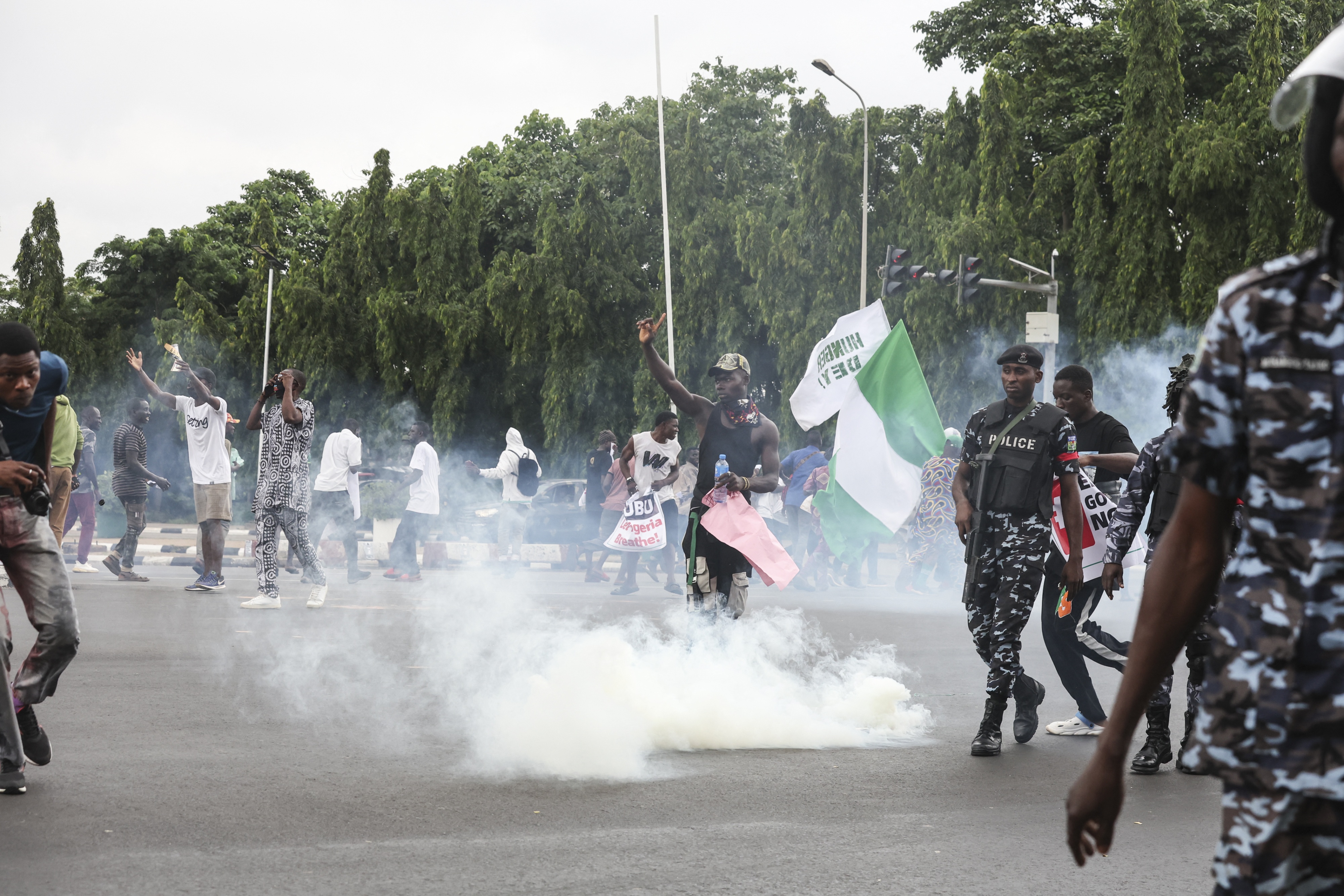 Demonstrators react as Nigerian policemen fire teargas canisters during the End Bad Governance protest in Abuja on August 1, 2024.