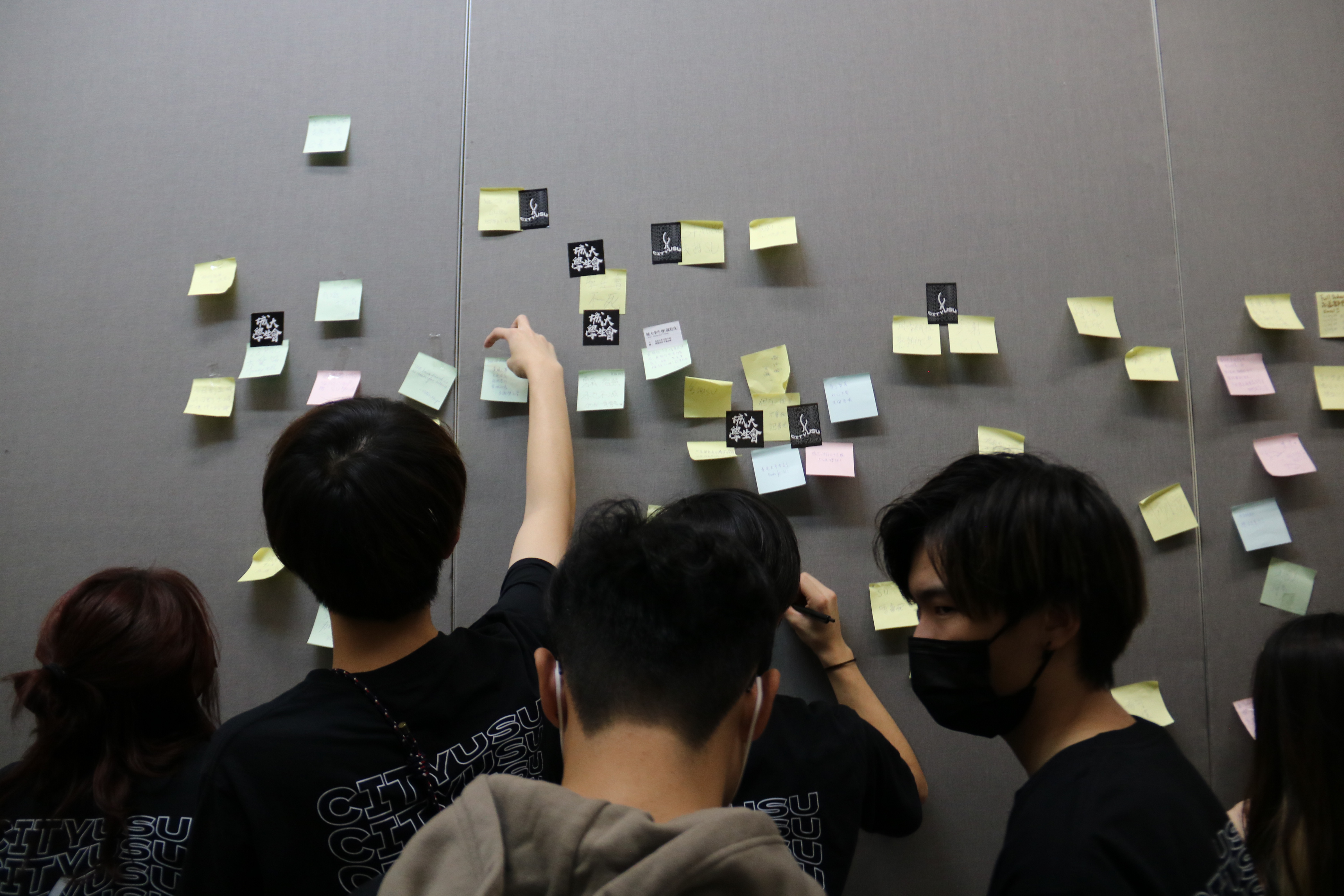 Students put post-it notes on a wall