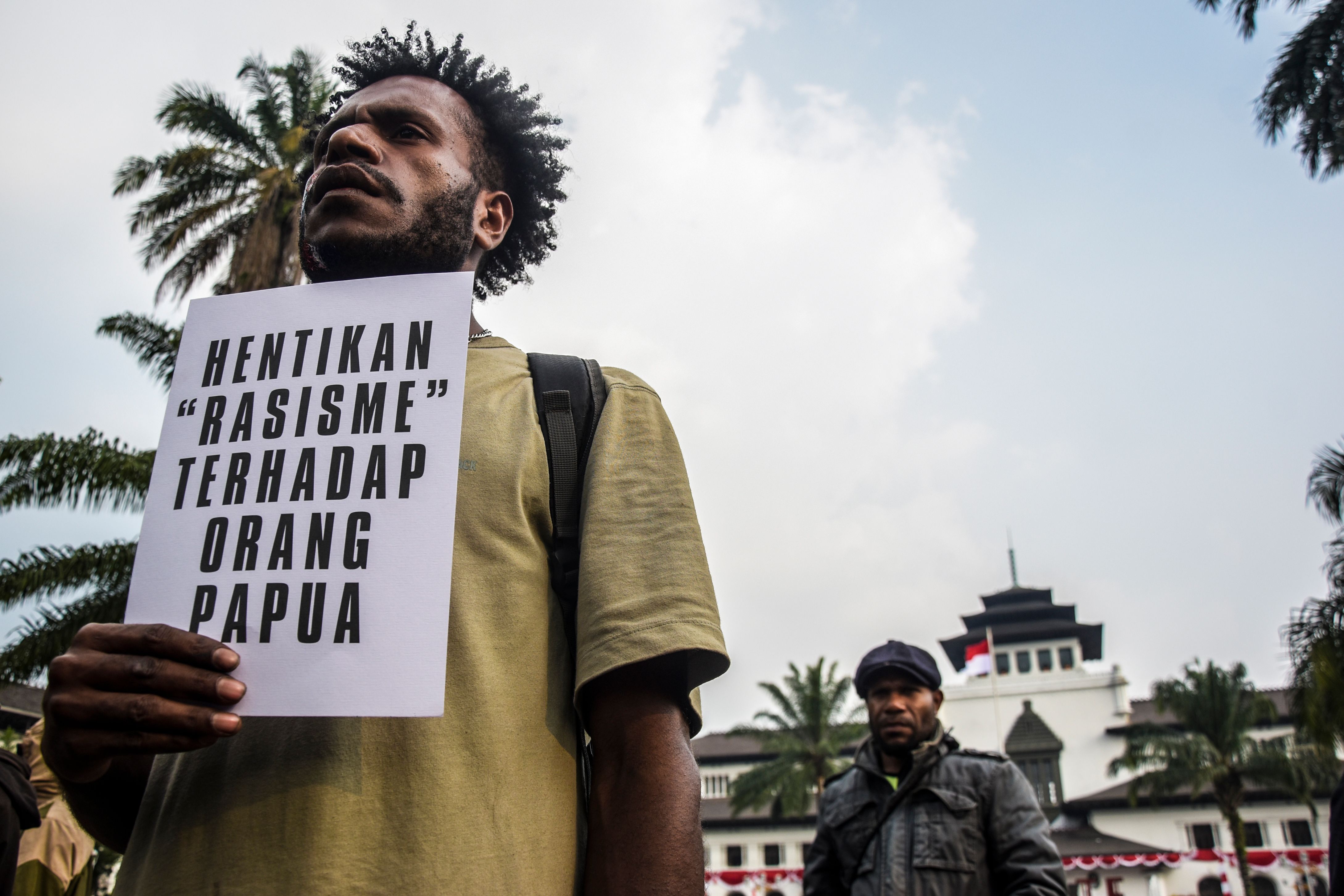 A man holds a sign in Indonesian at a protest