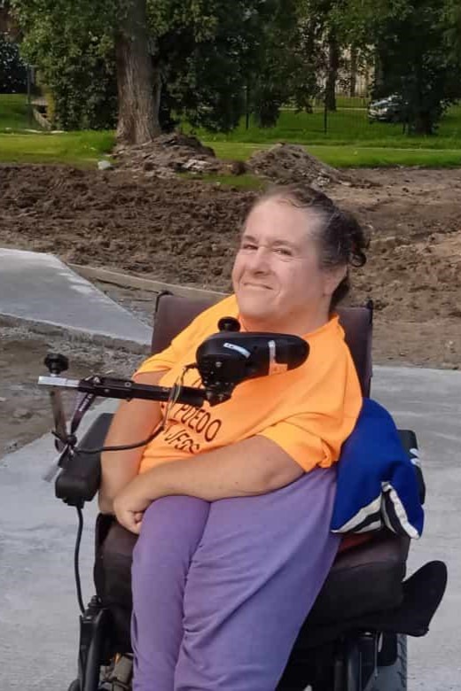 A woman poses for a photo in a wheelchair