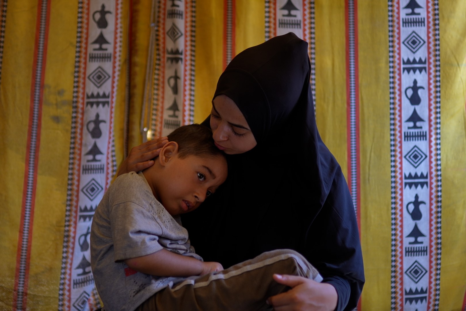 A woman holds her young son in her lap