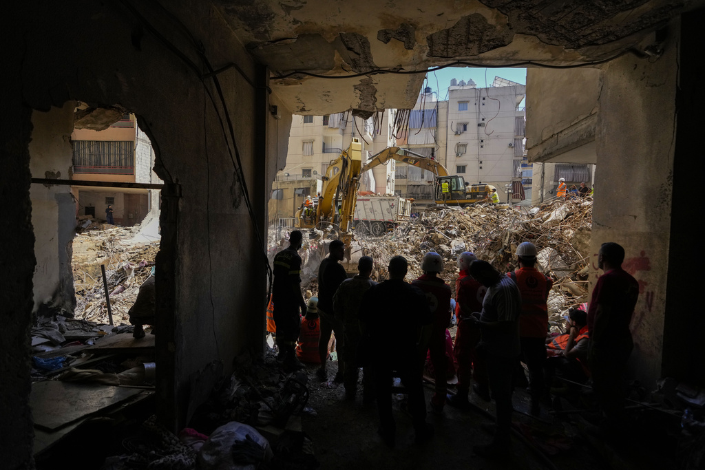 Des résidents libanais rassemblés au rez-de-chaussée d’un immeuble touché par une frappe israélienne dans la banlieue sud de Beyrouth regardaient une excavatrice qui déblayait les décombres devant l’édifice, le 23 septembre 2024.