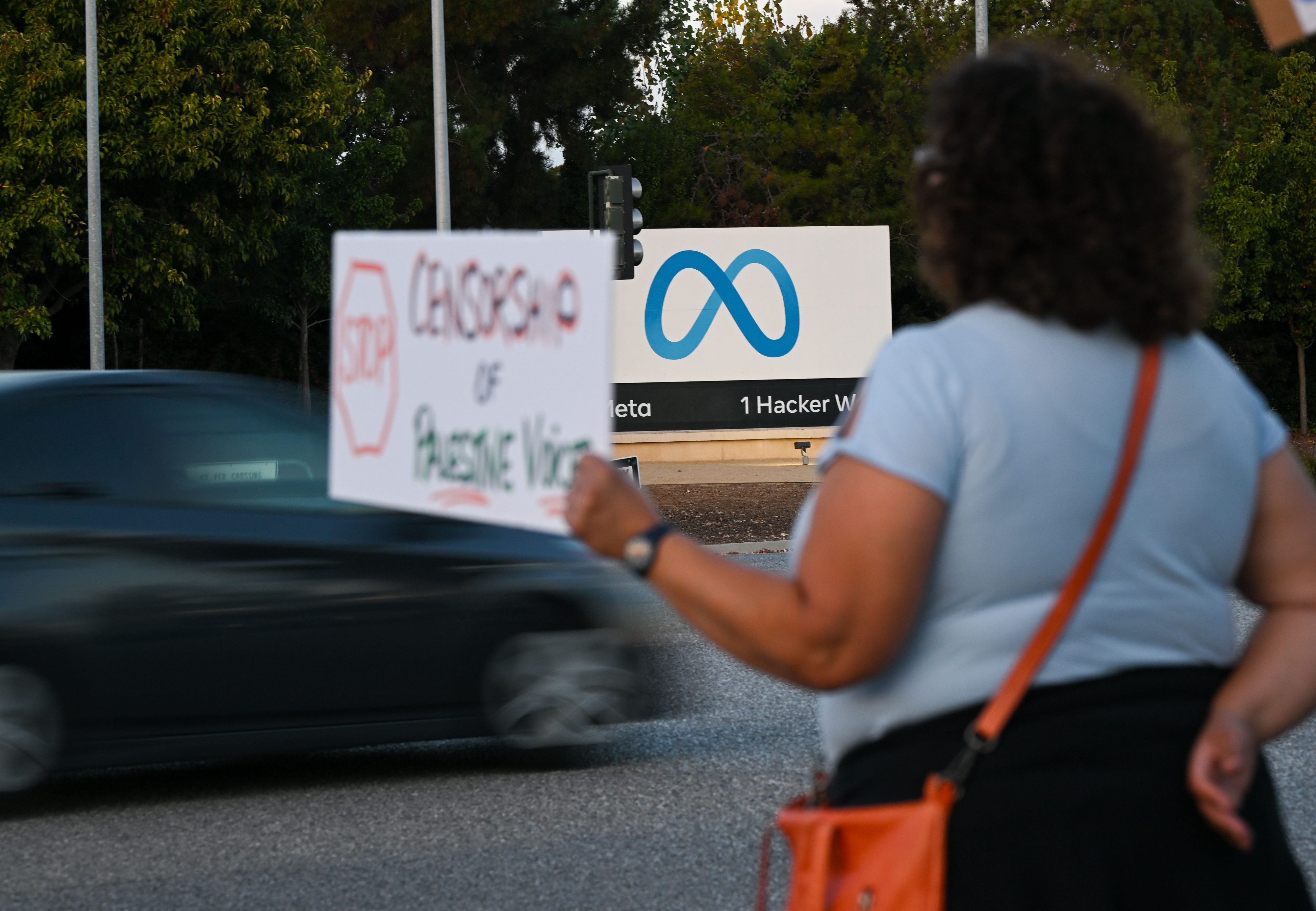 A person holding a protest sign outside of the Meta headquarters