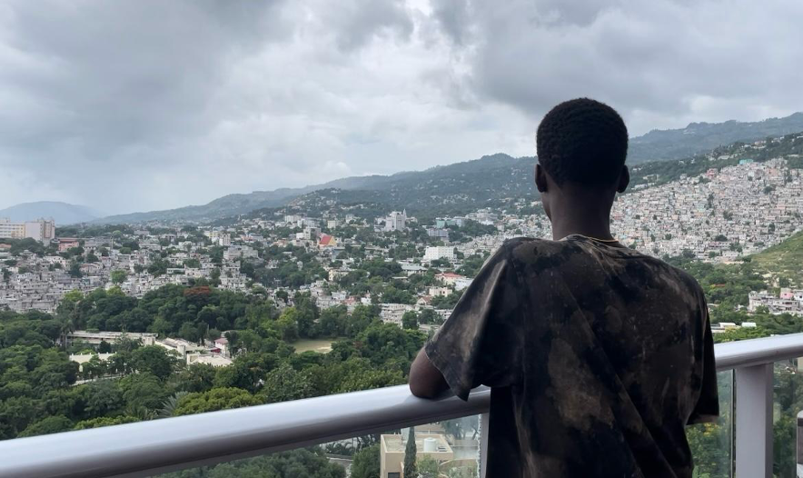 Un jeune habitant de Carrefour âgé de 17 ans, ayant des liens avec un groupe criminel, photographié de dos sur une terrasse avec une vue sur Port-au-Prince, en Haïti, en juillet 2024.