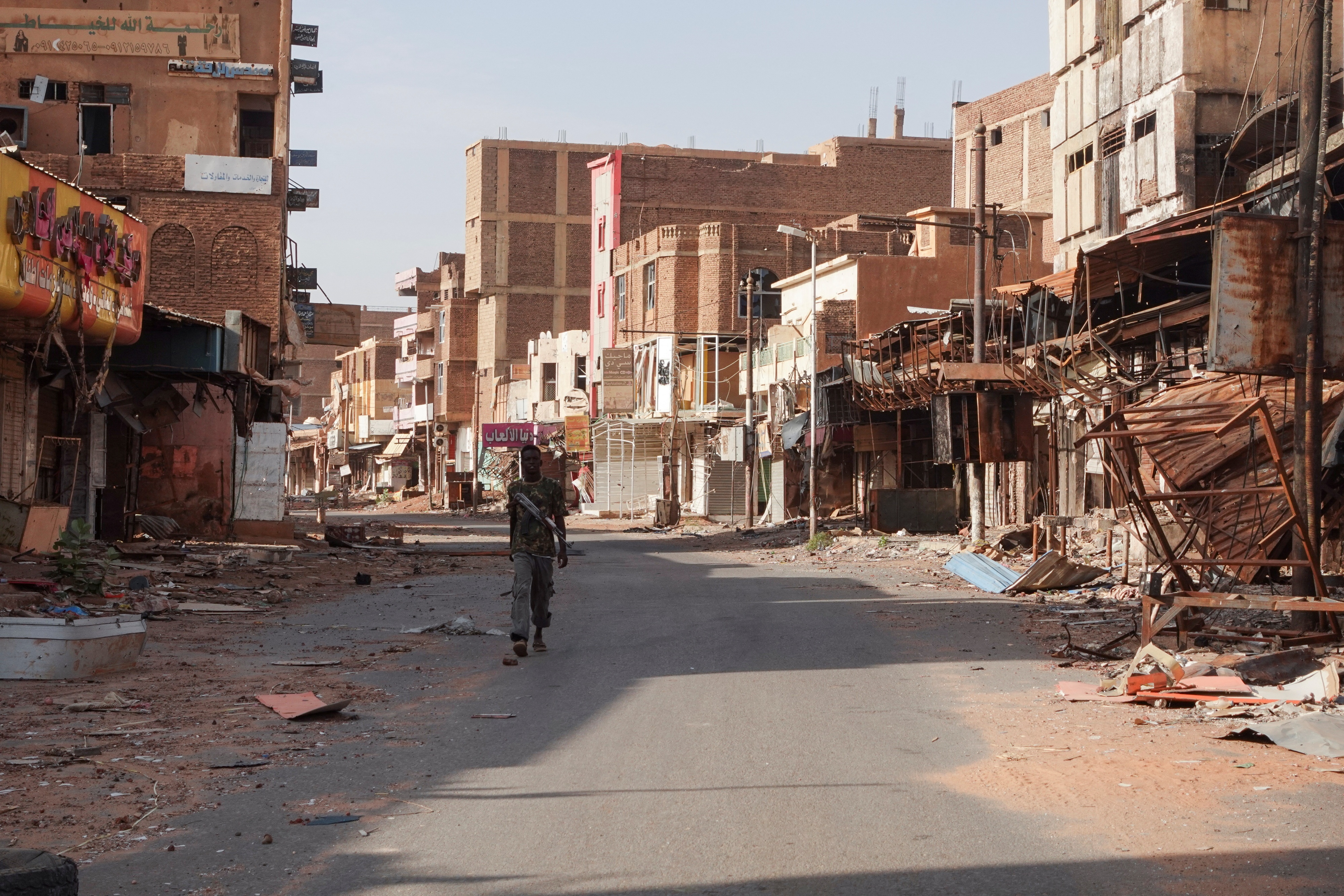 A member of the Sudanese Armed Forces (SAF) walks between damaged buildings, almost one year into the armed conflict between the Sudanese Armed Forces and the Rapid Support Forces (RSF), in Omdurman, Sudan, April 7, 2024.