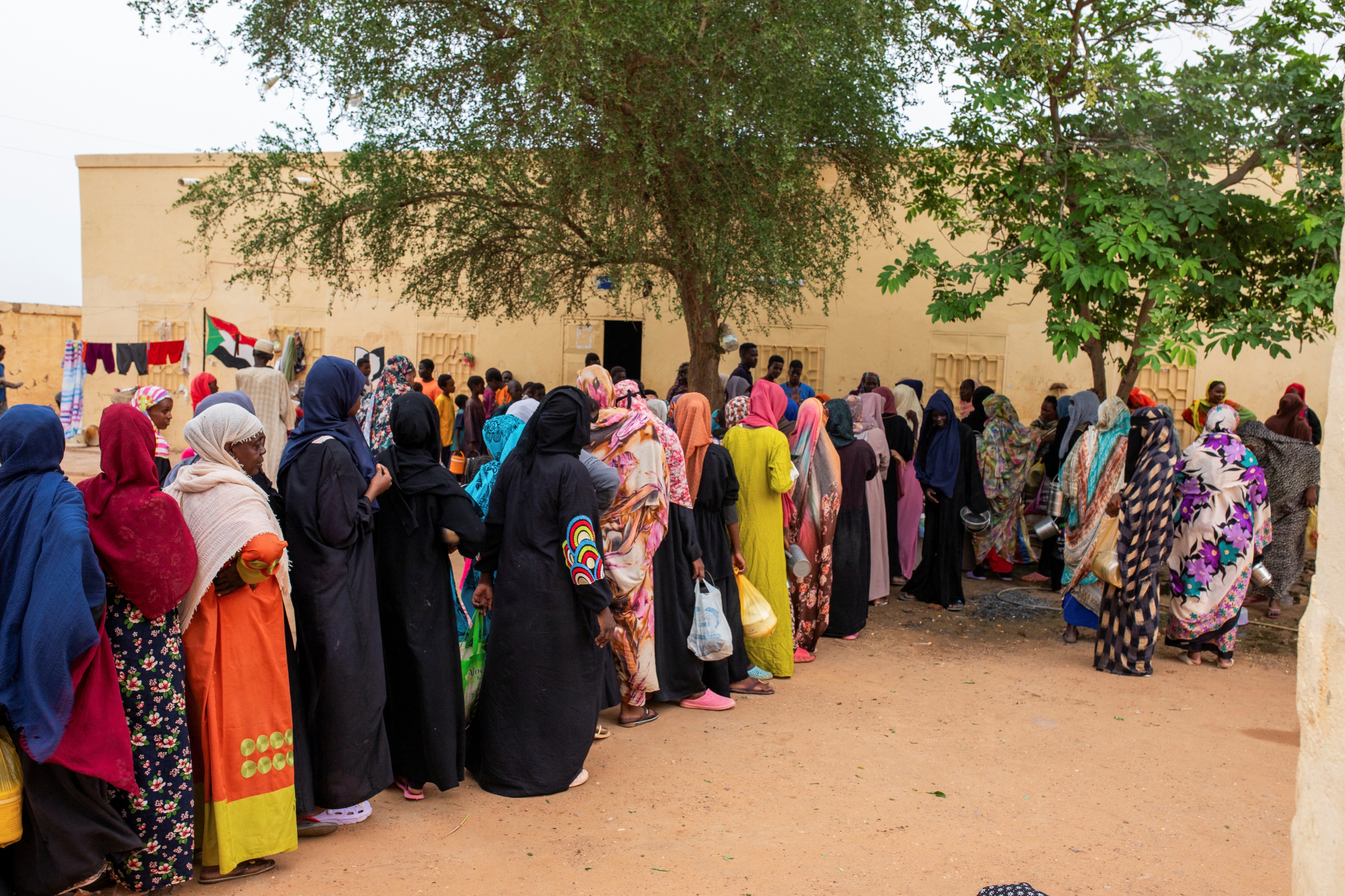 People from Sudan line up to receive food from community kitchens, run by local volunteers for people who are affected by conflict and extreme hunger and are out of reach of international aid efforts, in Omdurman, Sudan, August 22, 2024. 