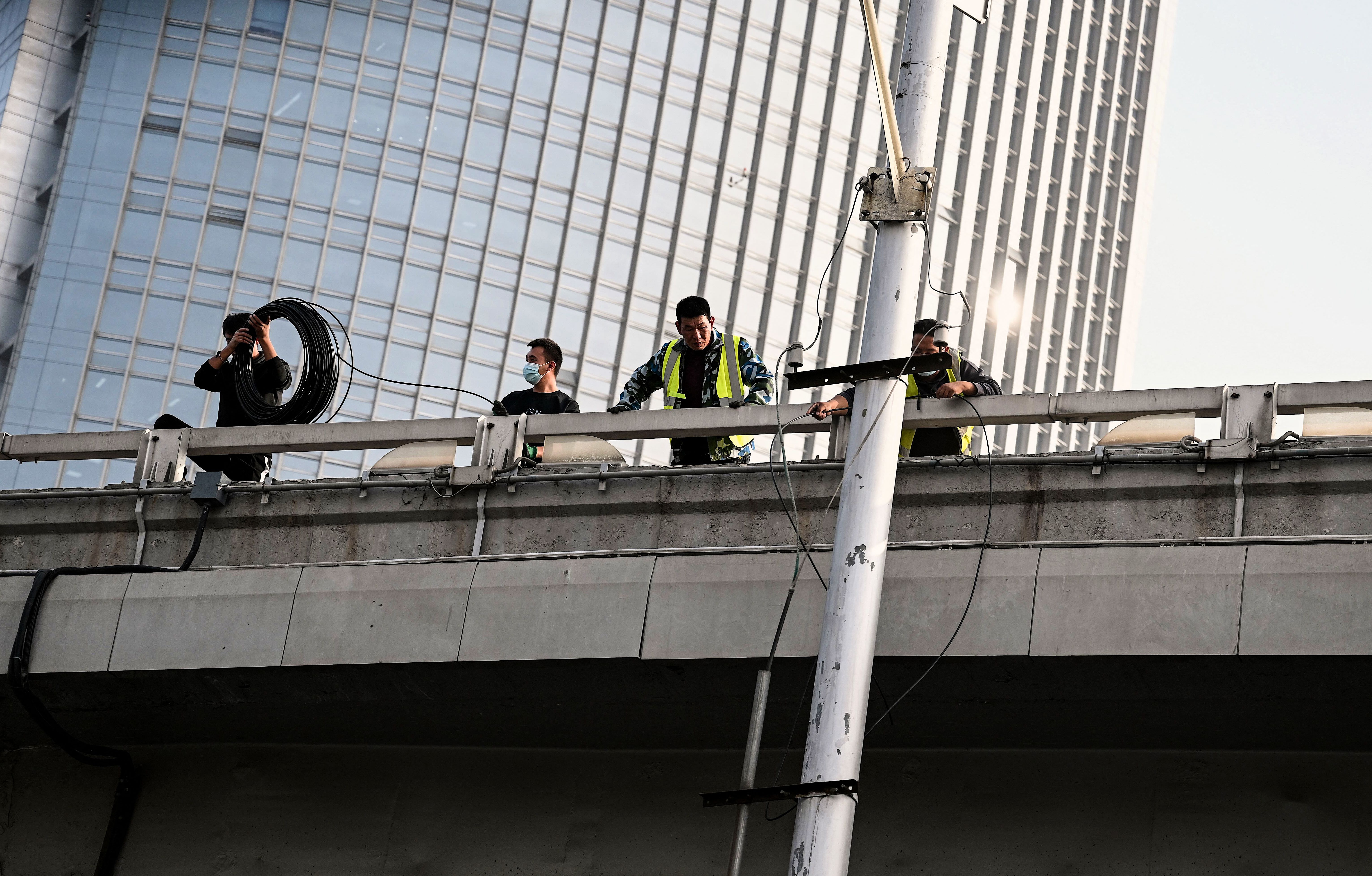 Workers are seen at the Sitong Bridge in Beijing on October 14, 2022, where protest banners with slogans criticizing the Communist Party's policies were hanged the day before.