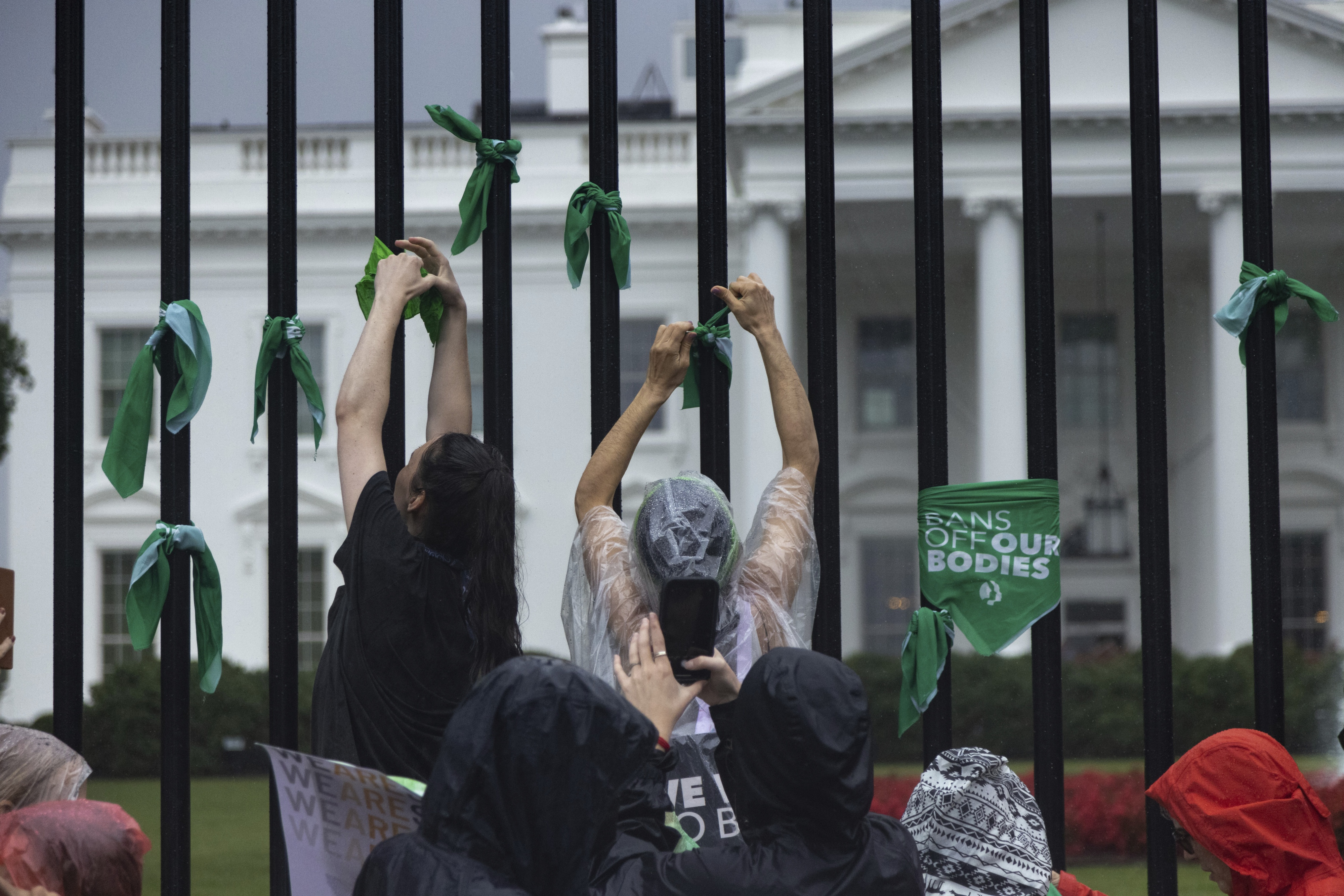 Abortion rights activists tie green bandanas reading “bans off our bodies” to the White House fence in Washington, DC, during a sit-in protest on July 9, 2022. 