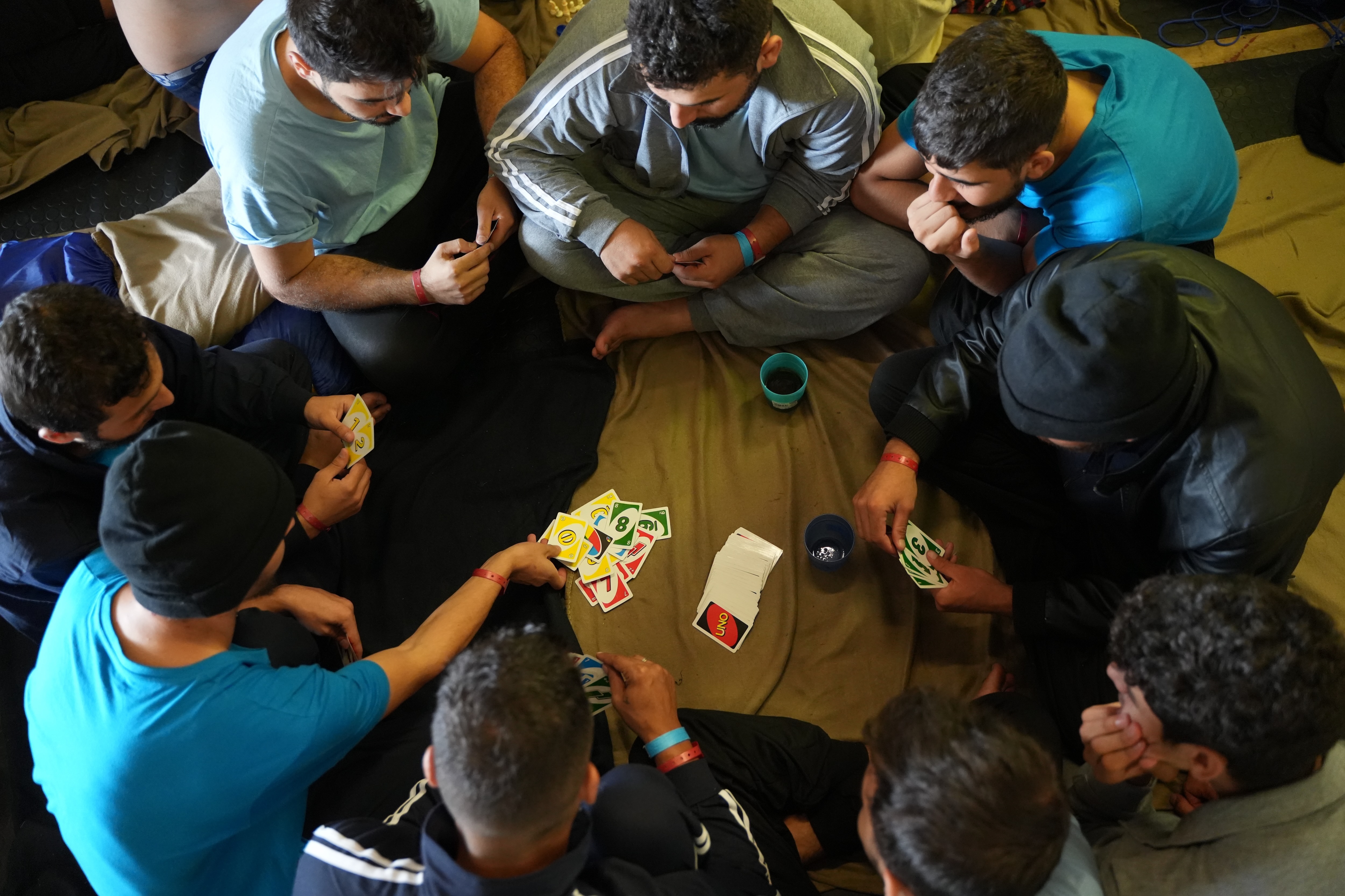 Survivors playing cards on the men’s “shelter deck” on the Geo Barents. 