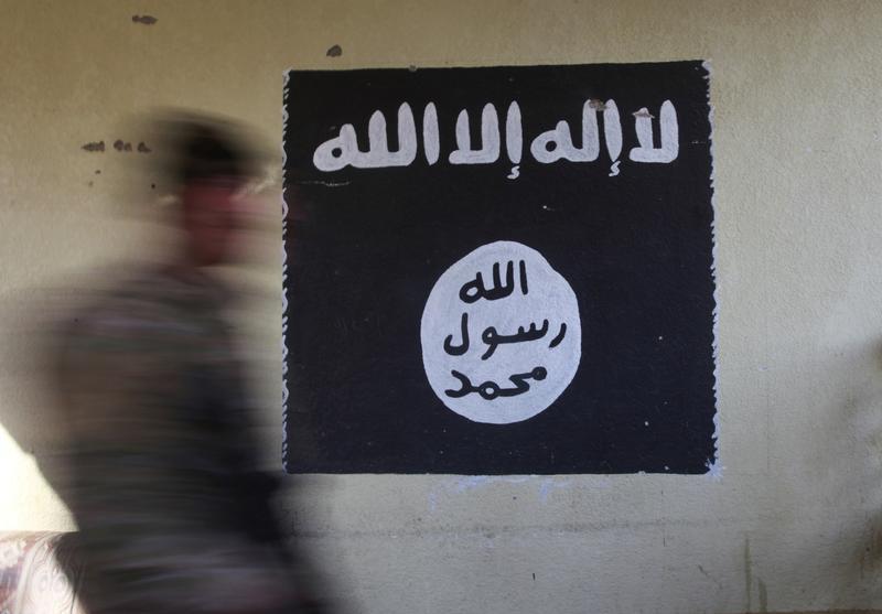 A member of the Iraqi security forces walks past a wall painted with the black flag commonly used by ISIS in Mosul, Iraq, January 8, 2017.