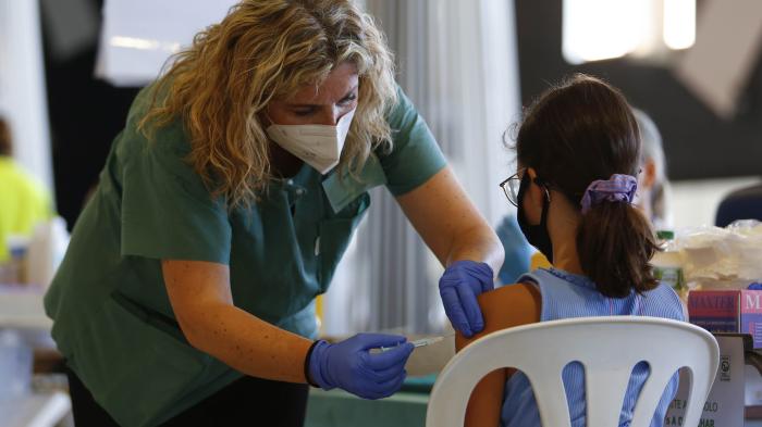 A nurse with a syringe explains and calms a girl while the COVID-19 vaccination goes on for children and young people in Granada, Spain on September 03, 2021. 