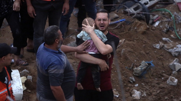 In the rubble of the Engineers’ Building, Karam al-Sharif, an UNRWA employee, holds one of his 18-month-old twin boys killed in the October 31 Israeli airstrike on the building that killed at least 106 civilians, including 5 of his children and 5 other relatives.
