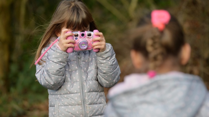 Two young girls are playing with their cameras in a garden, Osterode, Germany, January 8, 2016. 