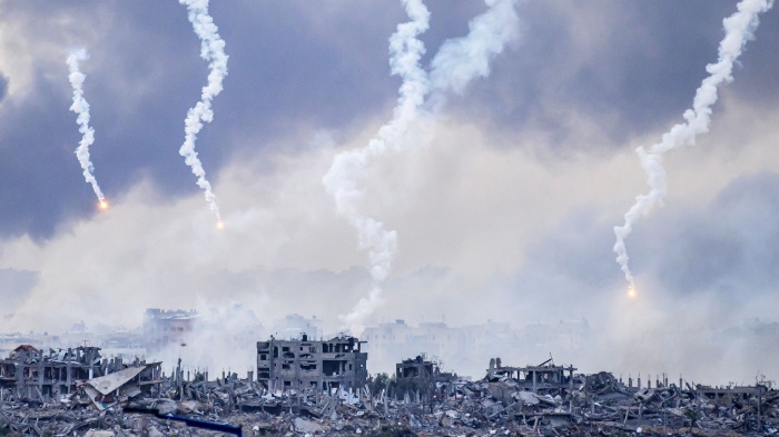 Smoke billows after an Israeli strike as flares are also dropped over north Gaza, November 22, 2023.