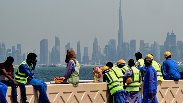 Workers sit on a wall against the backdrop of the city skyline, Dubai, UAE, March 11, 2026.