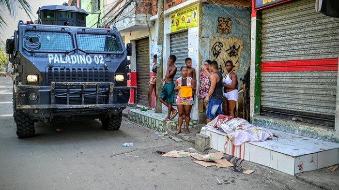 A military police armored vehicle passes by a person killed by police on April 7, 2016 in the Jacarezinho favela. Military police killed two other people during the same raid. © 2016 Carlos Cout 
