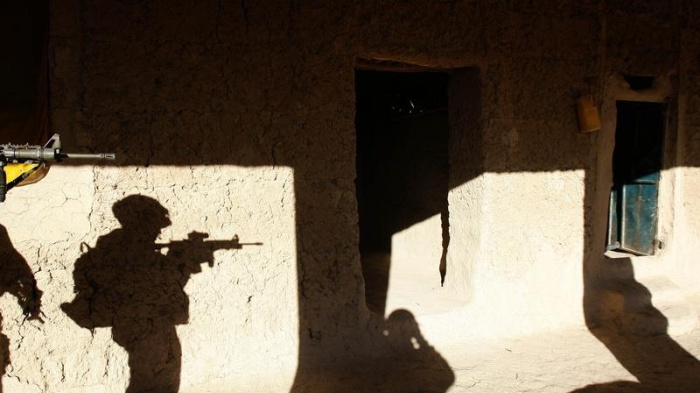 A US soldier searches a house in a village in Baluchi pass in Uruzgan province, November 1, 2004.