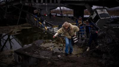 People flee across a destroyed bridge on the outskirts of Kyiv, Ukraine, March 2, 2022.