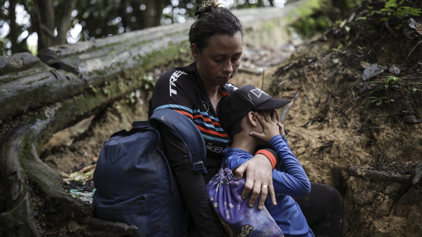 A woman embraces her son in a jungle