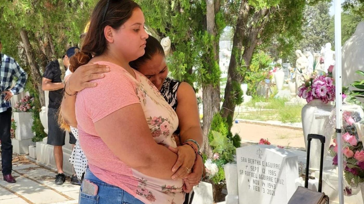 Two women embrace at a cemetery