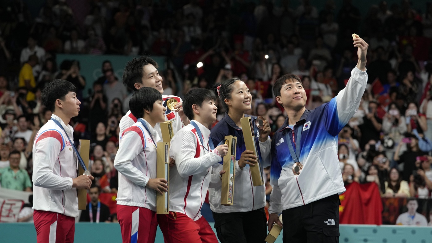 South Korea's Lim Jong-hoon, right, takes a selfie with other table tennis Olympians, including North Korea's Ri Jong Sik, left, and Kim Kum, second left, during the medal ceremony at the 2024 Summer Olympics in Paris, France, July 30, 2024.