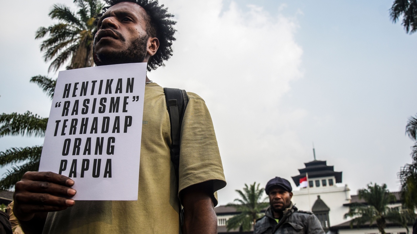 A man holds a sign in Indonesian at a protest