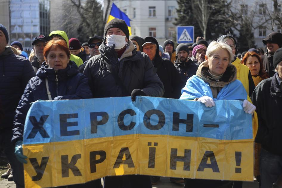 People hold a Ukrainian flag with a sign that reads: 