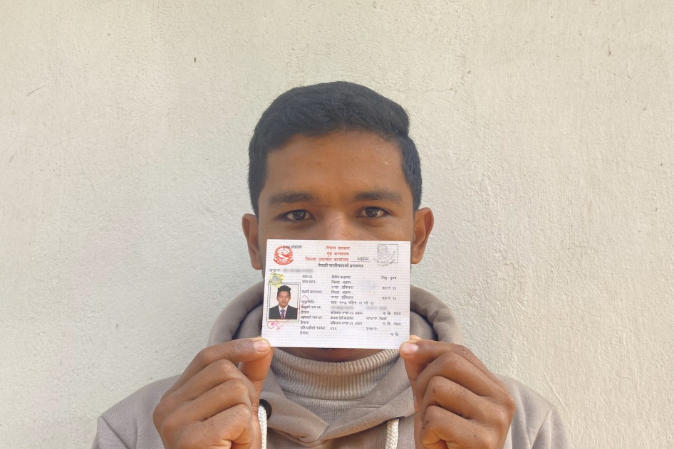 A man poses for a photo holding his ID card