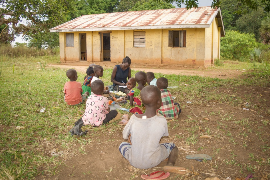 A teacher conducts a class outside with a group of small children