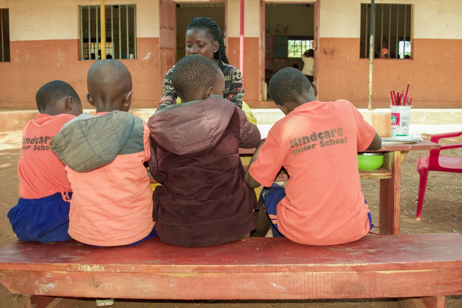 A teacher and students seated at a table outside a school building